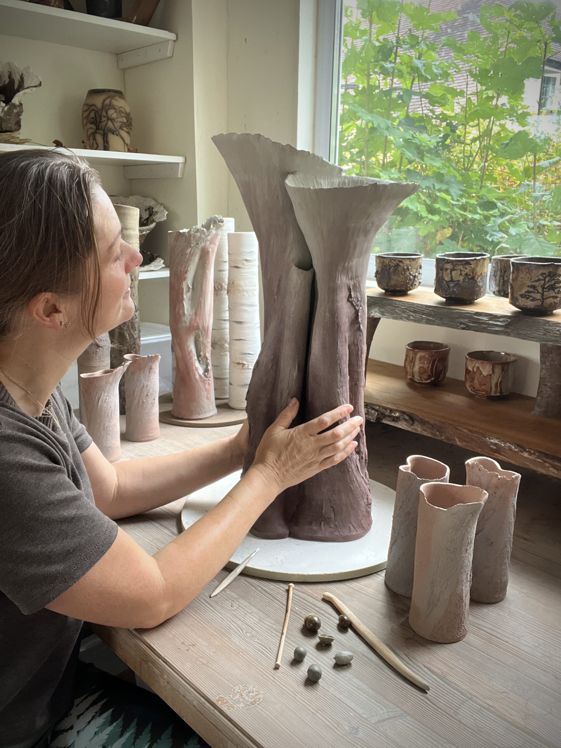 Sonya Wilkins holding a clay vessel inspired by an Oak Tree and translating her remember-ings from studying the tree into the clay using intention