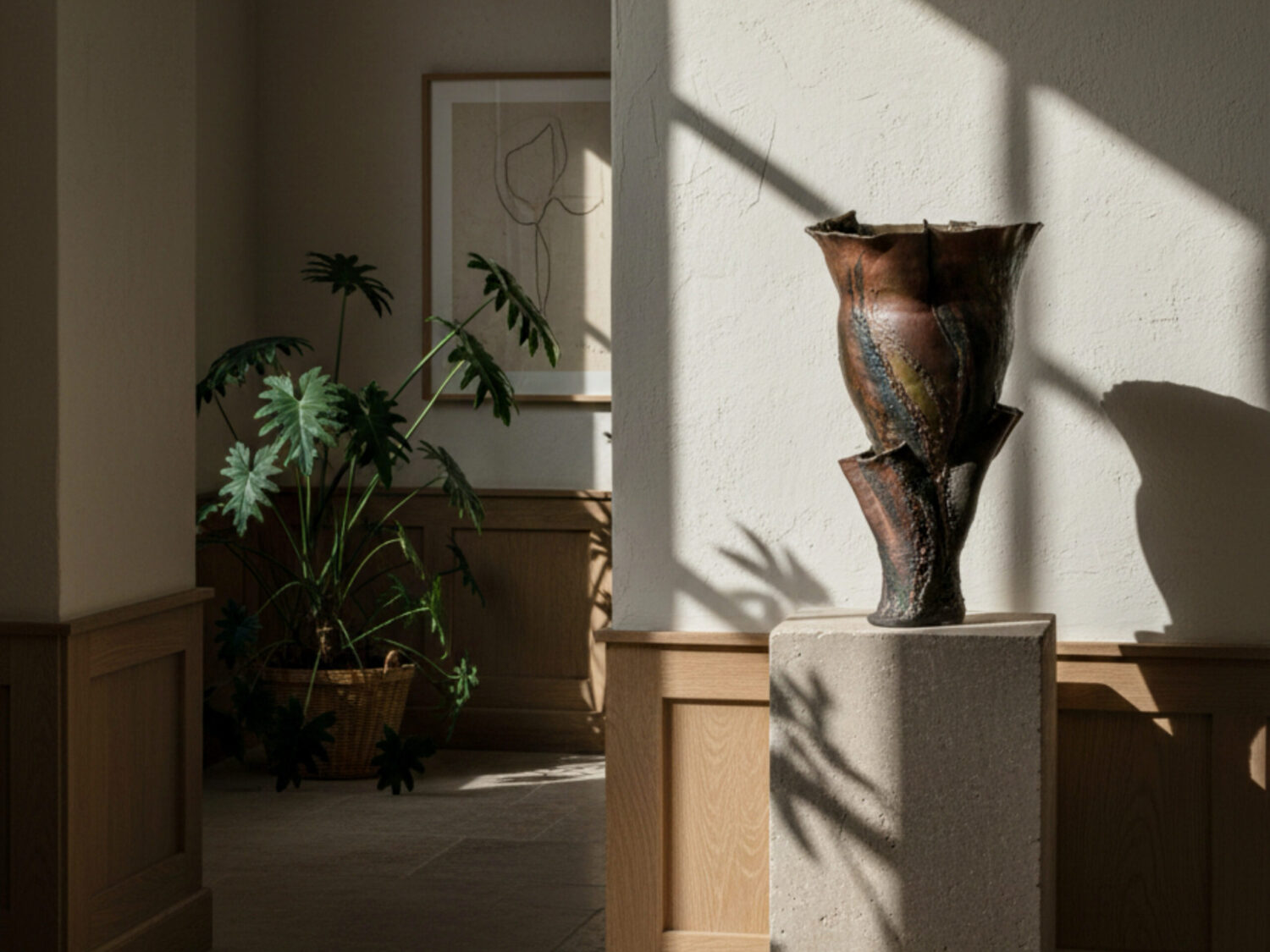 Brown sculptural vessel sat on plinth in gallery setting with dappled sunlight