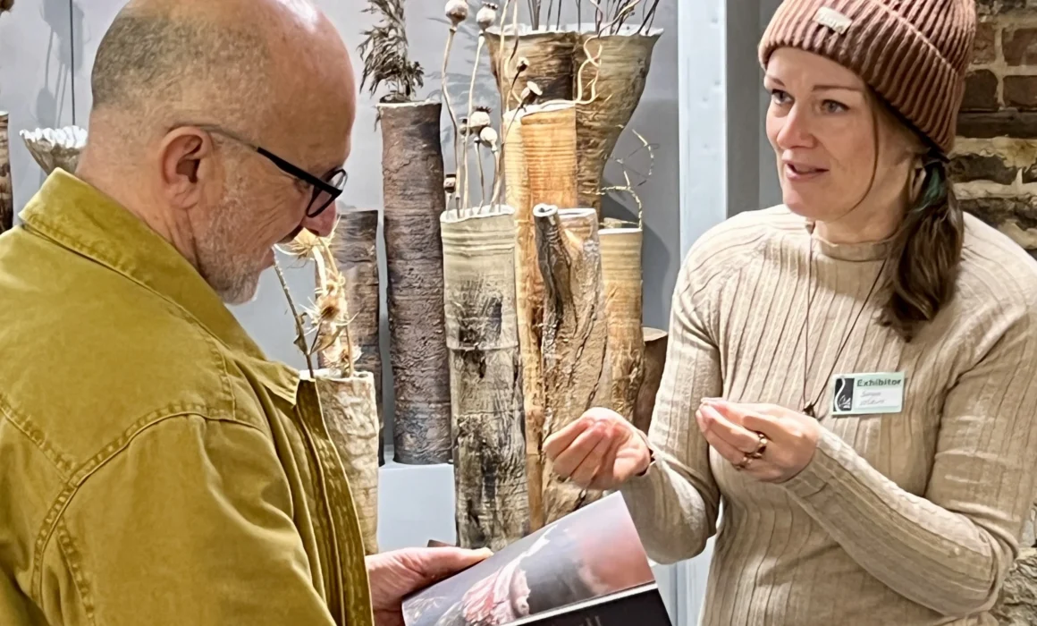 Sonya Wilkins talking to a customer about her passion for nature inspired ceramics in front her stand at Art in Clay Farnham