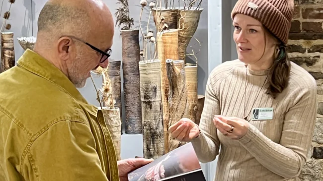 Sonya Wilkins talking to a customer about her passion for nature inspired ceramics in front her stand at Art in Clay Farnham